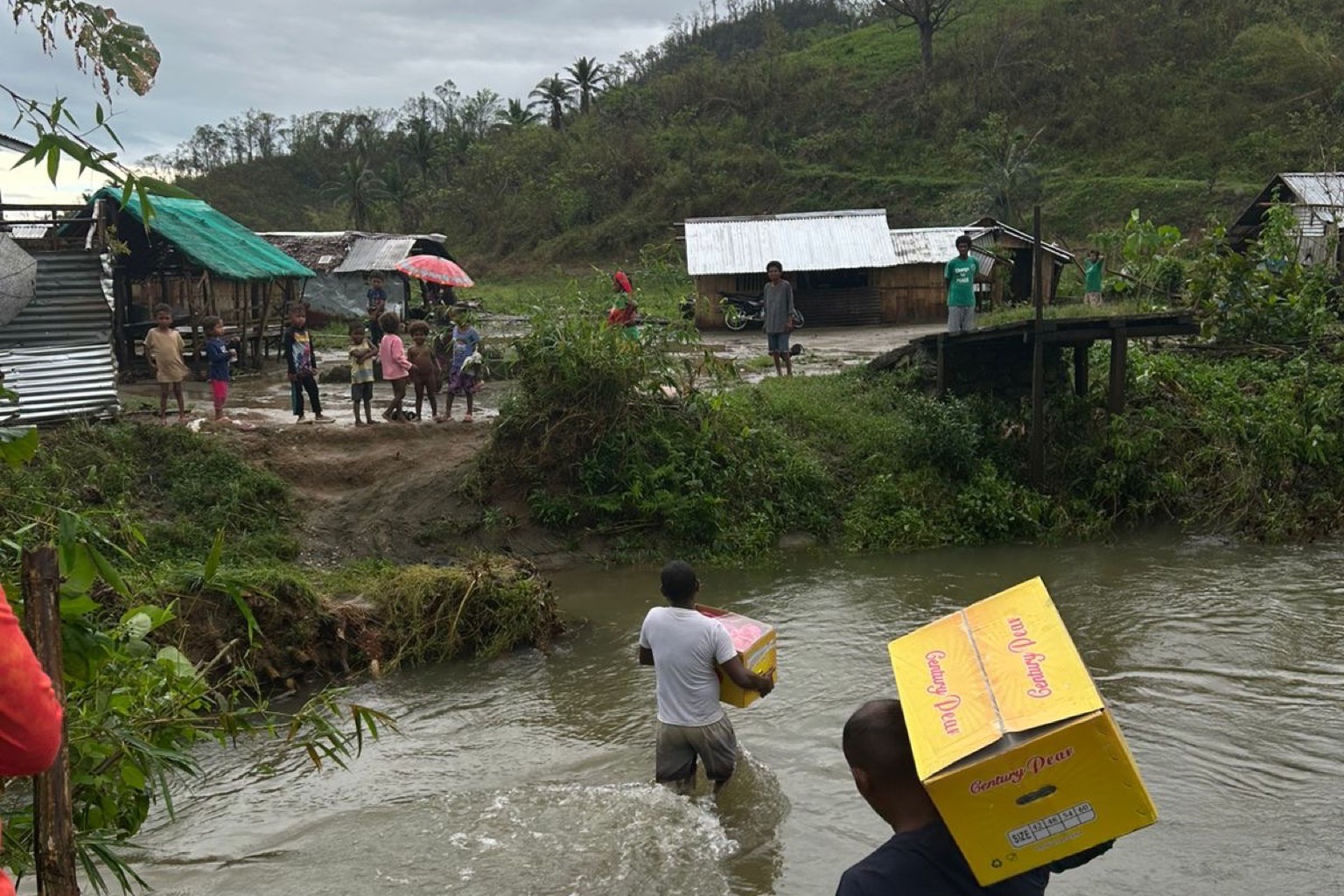Volunteers crossing a river carrying aid boxes